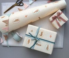 wrapping presents on a table with scissors, tape and other crafting supplies next to them