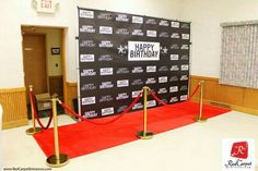 a red carpeted room with a happy birthday sign on the wall and barriers around it