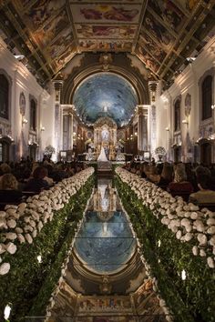 the inside of a church with flowers and greenery on the ground in front of it