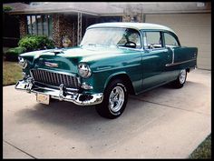 an old green car parked in front of a house