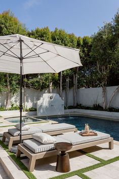 an outdoor patio with two lounge chairs and an umbrella over the pool area in front of it