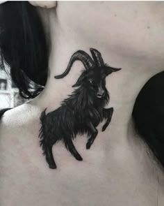 a black goat tattoo on the back of a woman's neck