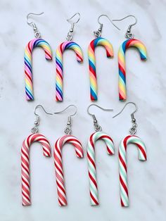 four candy canes are hanging from the earwires of some earrings on a marble surface