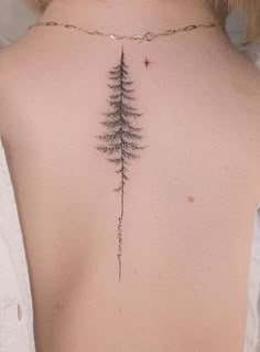 the back of a woman's neck with a pine tree tattoo on it