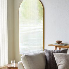 a living room filled with furniture and a large arched window in the wall above it