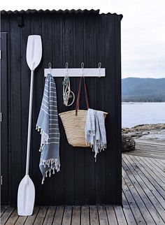 a black shed with two white paddles hanging from it's side and towels on the hooks