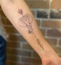 a small elephant tattoo on the left arm and wrist, with an arrow in the middle