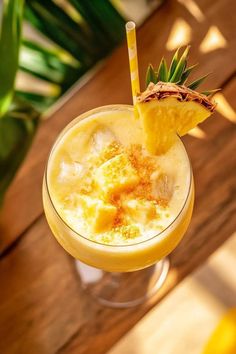 a close up of a drink in a glass on a table with a plant behind it