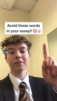 a young man wearing a suit and tie making the v sign with his fingers in front of him