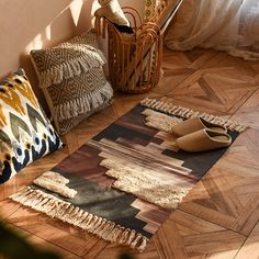 pillows and rugs are on the floor in front of a basket with decorative items