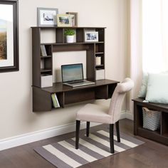 a computer desk with a laptop on it in front of a wall mounted bookcase