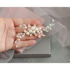 a woman's hand holding a wedding hair comb with pearls and crystals on it