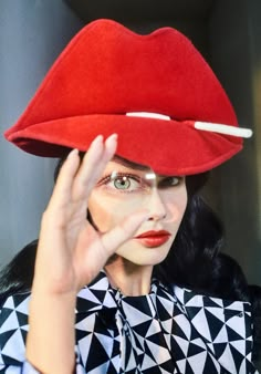 a woman wearing a red hat and holding her hand up to her face