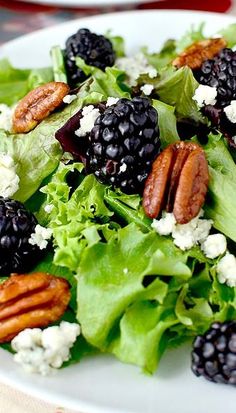 a salad with blackberries, cheese and pecans