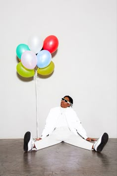 a man sitting on the floor in front of balloons