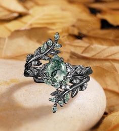 a ring with green stones and leaves on it