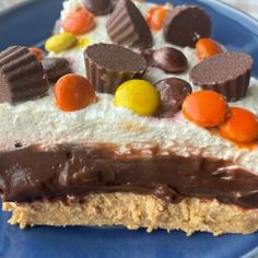 a piece of cake with chocolate and candy toppings on it's top, sitting on a blue plate