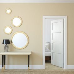 a table with a lamp and three mirrors on the wall