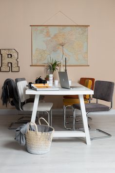 a white table topped with a laptop computer sitting next to a basket filled with books