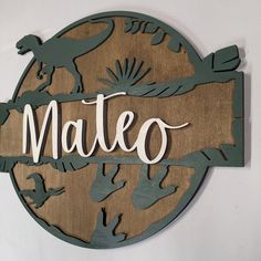 a wooden sign that says mateo with dinosaurs on the front and back of it