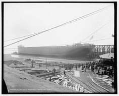 an old photo of a large boat being built on the water with people standing around it