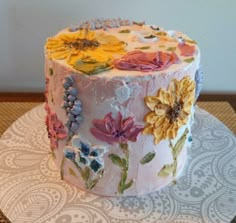 a decorated cake sitting on top of a white doily covered table next to a wall