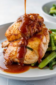 Grilled chicken breast with sauce being poured over, served on a bed of green vegetables. Chicken Breast Grilled, Different Sauces