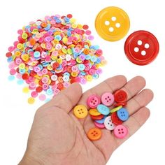 a hand is holding several different colored buttons