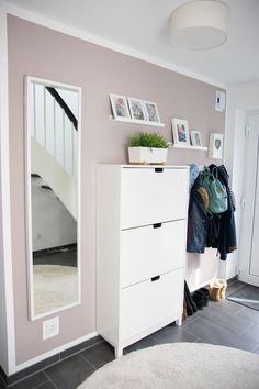 a white dresser sitting in front of a mirror next to a wall with pictures on it