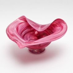 a pink glass bowl sitting on top of a white table