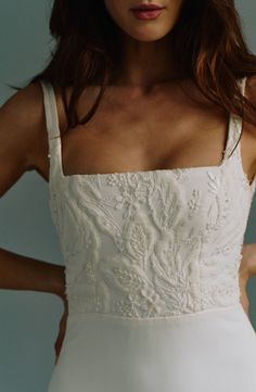 a woman in a white dress with her hands on her hips