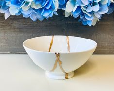 a white bowl sitting on top of a table next to blue flowers