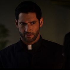 a man wearing a priest's collar in a dark room