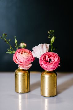 two gold vases with pink flowers in them