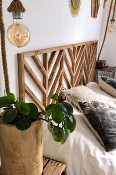 two potted plants sitting on top of a bed next to a wooden headboard