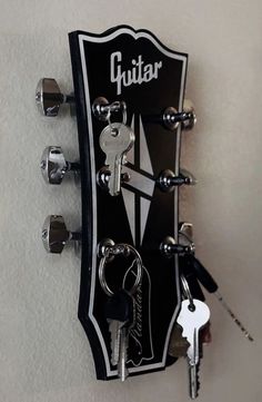 a guitar with keys attached to it hanging on the wall next to a key holder