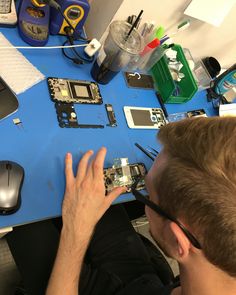 a man is working on some electronics at a table with his hands in front of him