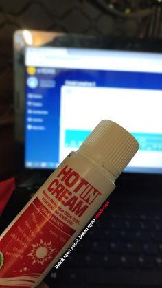 a bottle of cream sitting in front of a computer