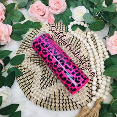 a pink and black leopard print tube sitting on top of a table next to flowers