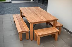 a wooden table and bench sitting on top of a tile floor next to a building