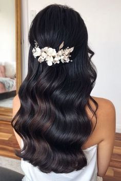 the back of a woman's head with long hair and flowers in her hair