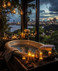 candles are lit in an outdoor jacuzzi tub overlooking the city lights and water