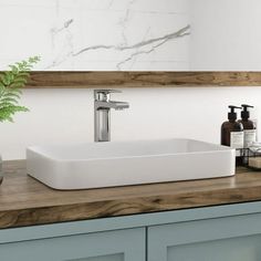 a white sink sitting on top of a wooden counter next to a vase filled with flowers