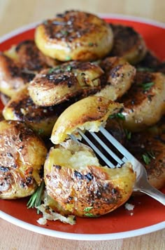 grilled potatoes on a red plate with a fork