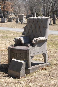 an old chair sitting in the middle of a cemetery with tombstones and headstones