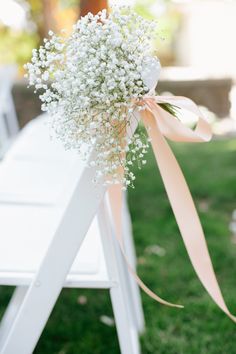 a bouquet of baby's breath sitting on top of a white chair in the grass