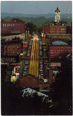 an aerial view of a city street with buildings and a clock tower in the distance