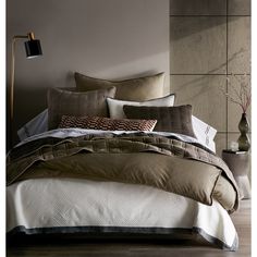 a bed with brown and white comforters on top of it next to a lamp