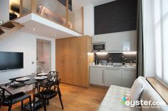 a kitchen and dining area with white walls, wood floors and ceiling lighting is shown in this modern apartment