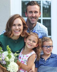 a man, woman and two children are posing for a photo with flowers in their hands